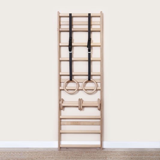 Wooden gym rings hanging from a MowoFit Wall Bar, highlighting the modular calisthenics equipment setup.