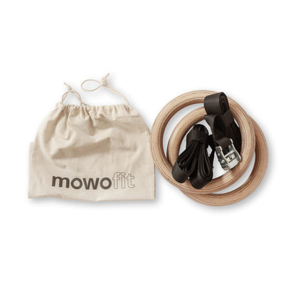 Gymnastic rings suspended from wooden MowoFit S-hooks on a wall bar for calisthenics training.