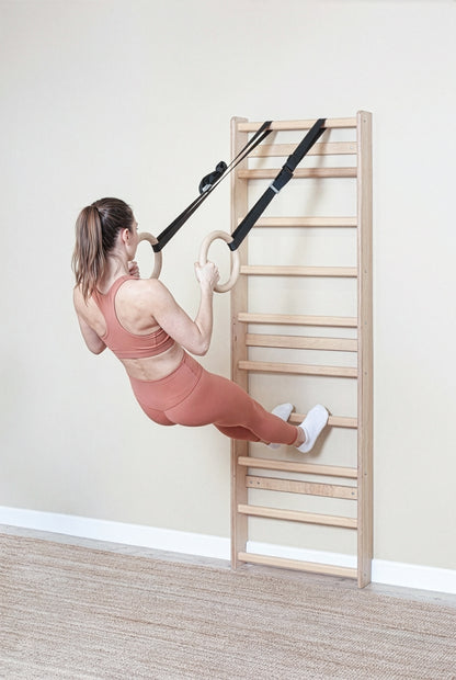 Fit model performing calisthenics exercises on a MowoFit modular wall bar, showcasing the premium handcrafted solid Beech wood design in a modern minimalist space.