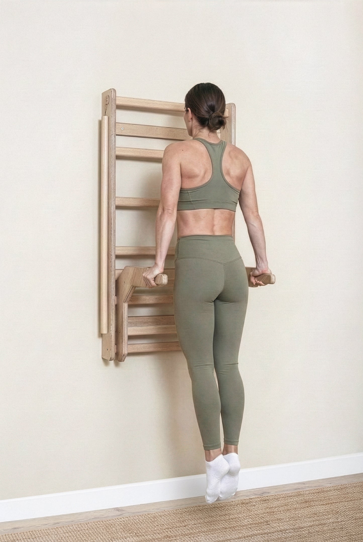 Fit model performing calisthenics exercises on a MowoFit modular wall bar, showcasing the premium handcrafted solid Beech wood design in a modern minimalist space.